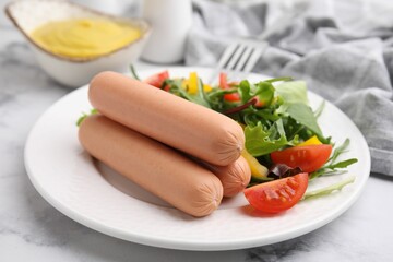 Delicious boiled sausages with salad on table