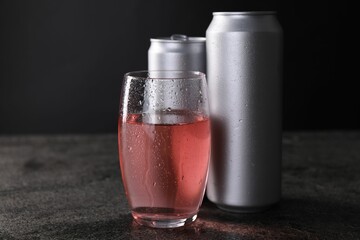 Energy drink in glass and aluminium cans on grey table, closeup