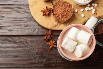 Tasty hot chocolate with marshmallows and ingredients on wooden table, flat lay. Space for text