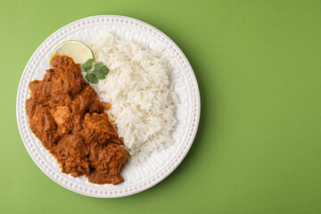 Delicious chicken curry with rice on green background, top view. Space for text