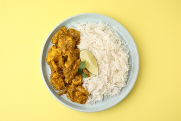 Delicious chicken curry with rice on yellow background, top view