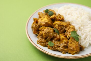 Delicious chicken curry with rice on green background, closeup