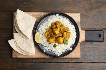 Delicious chicken curry with rice and tortillas on wooden table, top view