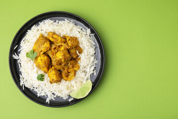 Delicious chicken curry with rice on green background, top view. Space for text