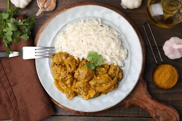 Delicious chicken curry with rice and ingredients on wooden table, flat lay