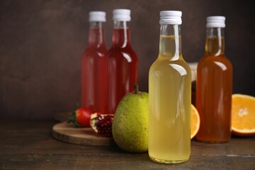 Delicious kombucha in glass bottles and fresh fruits on wooden table