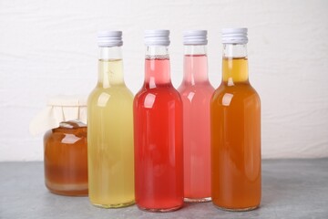 Delicious kombucha in glass bottles and jar on grey table against white background