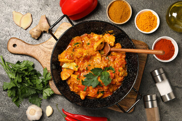 Delicious chicken curry and ingredients on grey table, flat lay