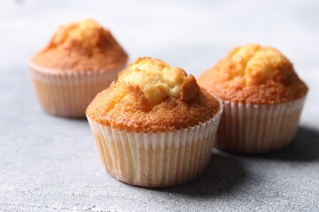 Delicious sweet muffins on light grey textured table, closeup