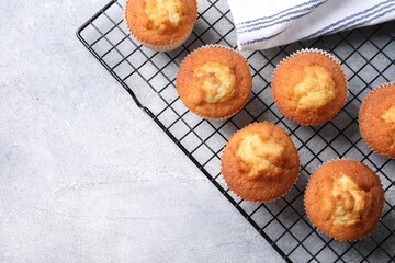 Delicious sweet muffins on light grey textured table, top view. Space for text