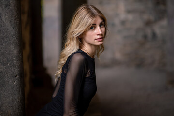 Fototapeta premium Blonde girl in black dress looking over shoulder