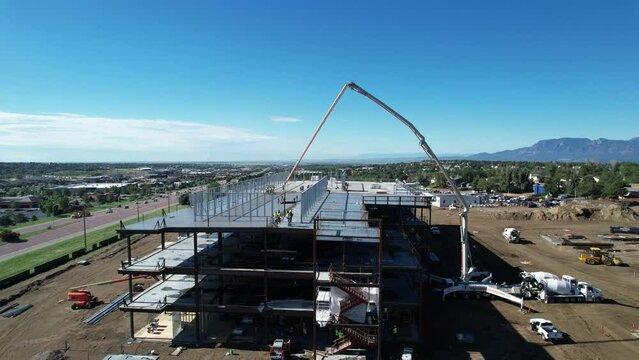 Aerial 360 view of construction workers pouring concrete on a commercial building