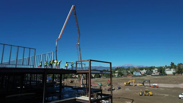 Aerial view of construction workers pouring concrete on a commercial building near the mountains