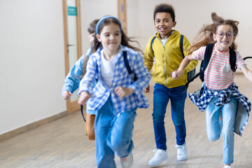 Group of elementary school kids running in school corridor.