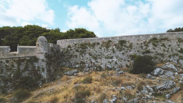 Fortress of Rethymno surrounded by sea in Crete. Drone video of venetian fortress old stone wall in Crete, Greece. Ancient medieval site in Greece. Famous archaeological site near the sea in Crete.