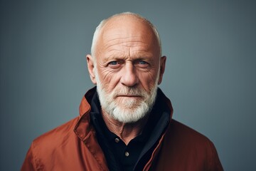 Portrait of an elderly man with white beard in a red jacket.