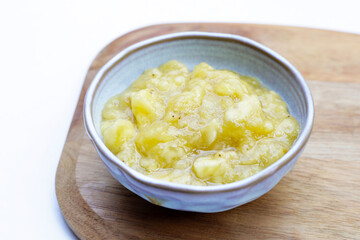 Mashed banana in bowl on white background.