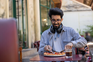 Young hindu man eating pizza in pizzeria