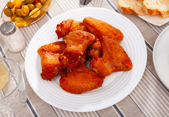 Crispy smoked chicken wings served in a flat plate with other table appointments