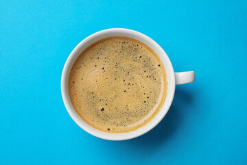 Aromatic coffee in cup on light blue background, top view