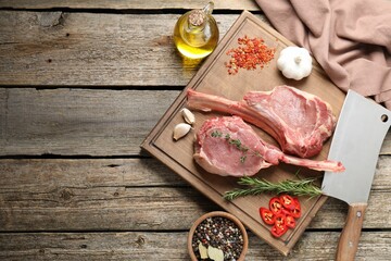 Fresh tomahawk beef cuts, butcher knife and spices on wooden table, top view. Space for text