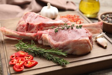 Fresh tomahawk beef cuts and spices on wooden table, closeup