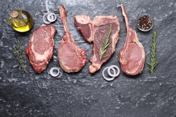 Fresh raw beef cuts and different spices on grey textured table, flat lay. Space for text