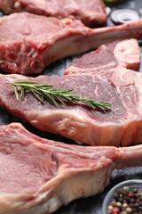 Fresh raw beef cuts and different spices on table, closeup