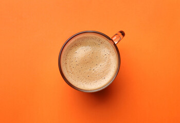 Fresh coffee in cup on orange background, top view