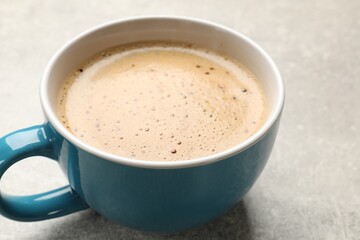 Cup of aromatic coffee on light grey table, closeup