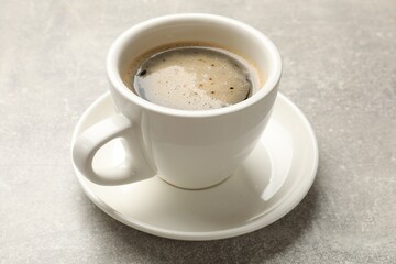 Cup of aromatic coffee on light grey table, closeup.