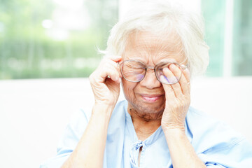 Asian senior woman wearing eyeglasses reduce headache and eyestrain suffer at home care service.