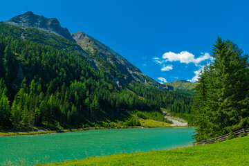 mountain lake Schlierersee, Lungau Austria in pine trees. green water of lake on blue sky background. mountain landscape and lake