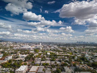 Aerial panorama of residential neighborhood streets of West Hollywood and city of Los Angeles cityscape panorama with fluffy clouds, downtown LA skyline in background - 729702629