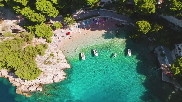 Breathtaking aerial view of pebble beach with turquoise waters and sunbathers in Brela, Croatia. Popular tourist destination in summer.