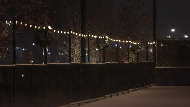 Snow falling on an empty courtyard with wreaths and lights