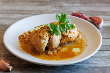 Glazed Chicken breast in a honey Sweet and Sour marinade with garlic and orange juice on white plate on wooden table close up