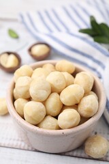 Tasty peeled Macadamia nuts in bowl on light table