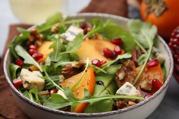 Tasty salad with persimmon, blue cheese, pomegranate and walnuts served on table, closeup