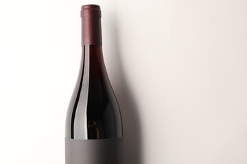 Bottle of tasty red wine on white background, top view. Space for text