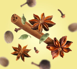 Different aromatic spices falling on yellow background