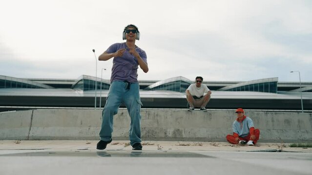 Group of asian break dancer perform street dance with multicultural friend support and moving hip hop music. Attractive handsome hipster practice b boy dance at street. Outdoor sport 2024. Sprightly.