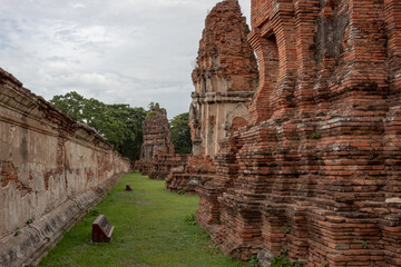 Stone red brick Thai temple pagoda ruin and trees of Wat Maha That historical park in Ayutthaya Thailand on a cloudy day	