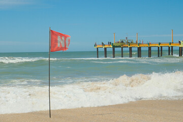 Flag with bathing ban develops in the wind, Atlantic coast beach, Villa Gesell, Argentina,...