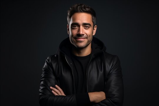 Portrait of a handsome young man in a black leather jacket on a dark background.