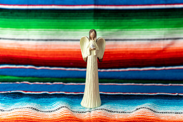 Beautiful angel holding dove figurine with Mexican blanket as backdrop.