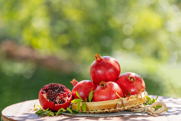 ชื่อ	
Pomegranate in wooden basket on wooden table in garden, Pomegranate with slices on blurred greenery background.	
