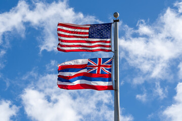 Flag of the United States and flag of Hawaii with blue sky background. 