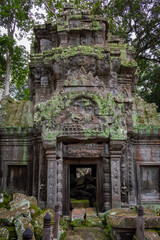 Fototapeta na wymiar Green moss-covered stone pagoda building door entrance and bricks at Ta Prohm Tomb Raider temple ruin complex Angkor Wat historical site, Siem Reap, Cambodia