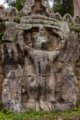 Moss covered stone temple statue carcing ruin building complex Angkor Wat historical park site in the forest of Siem Reap Cambodia